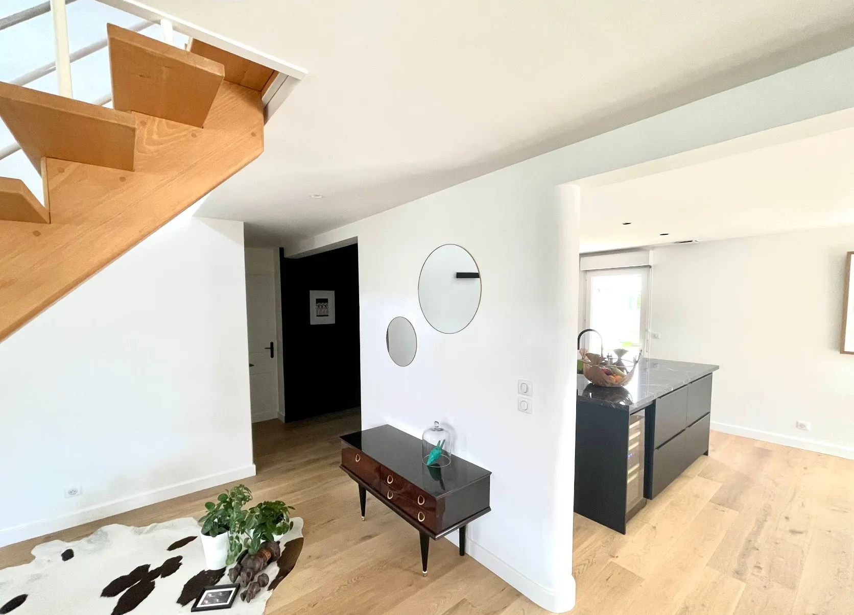 Entree avec mur sombre et cuisine en arriere-plan